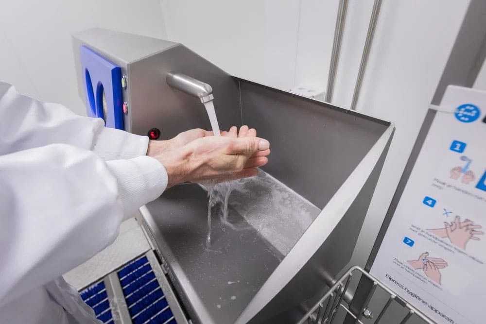 Operatore alimentare che si lava le mani in una postazione automatica con istruzioni visive HACCP